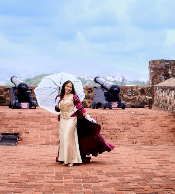 Quinceañera con vestido color vino posando en monumento histórico de Puerto Plata.