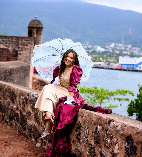 Quinceañera con vestido color vino posando en monumento histórico de Puerto Plata.